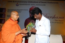Swami Jitakamananda presenting bouquet to Sri Kota Srinivas Poojari